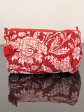 red toiletry bag with floral pattern sitting on a glass surface