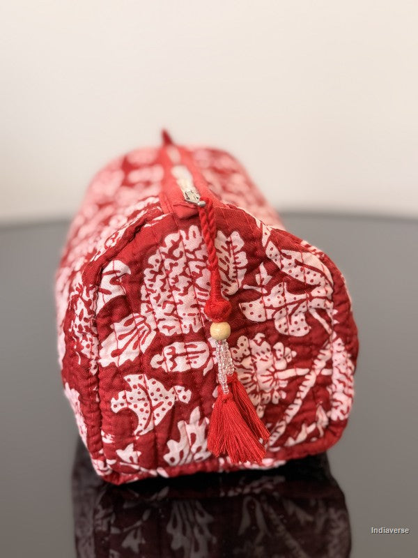 red toiletry pouch with red tassel sitting on a glass surface