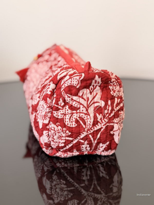 red toiletry pouch with red tassel sitting on a glass surface