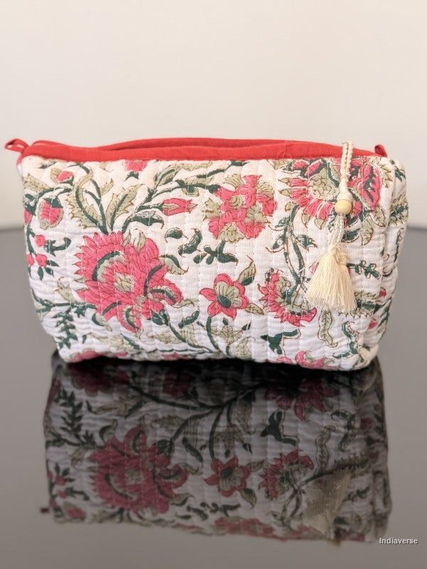 Floral patterned pouch with a tassel on a reflective surface