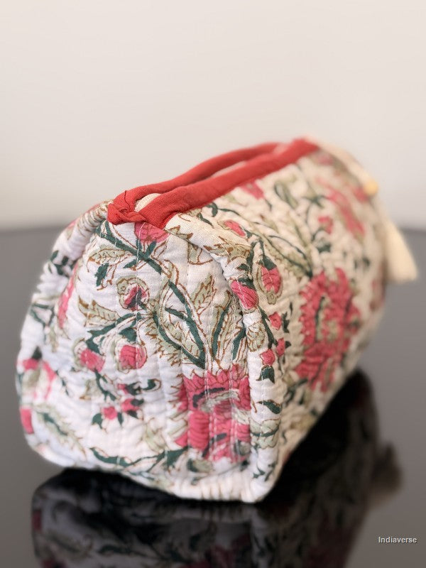 Floral-patterned fabric pouch with red accents on a reflective surface