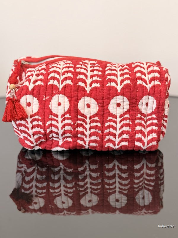 Red and white patterned bag with tassel on a reflective surface