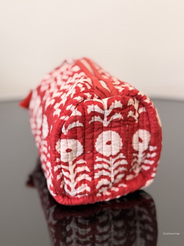 red toiletry bag with white flowers sitting on a glass surface