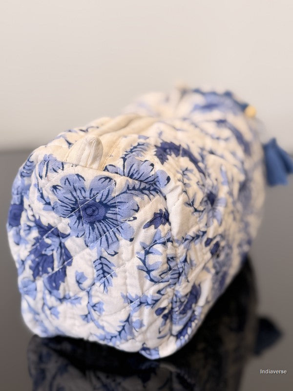 Blue and white floral-patterned fabric roll on a reflective surface with a neutral background