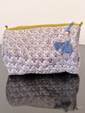 blue toiletry bag with small flowers sitting on a glass surface