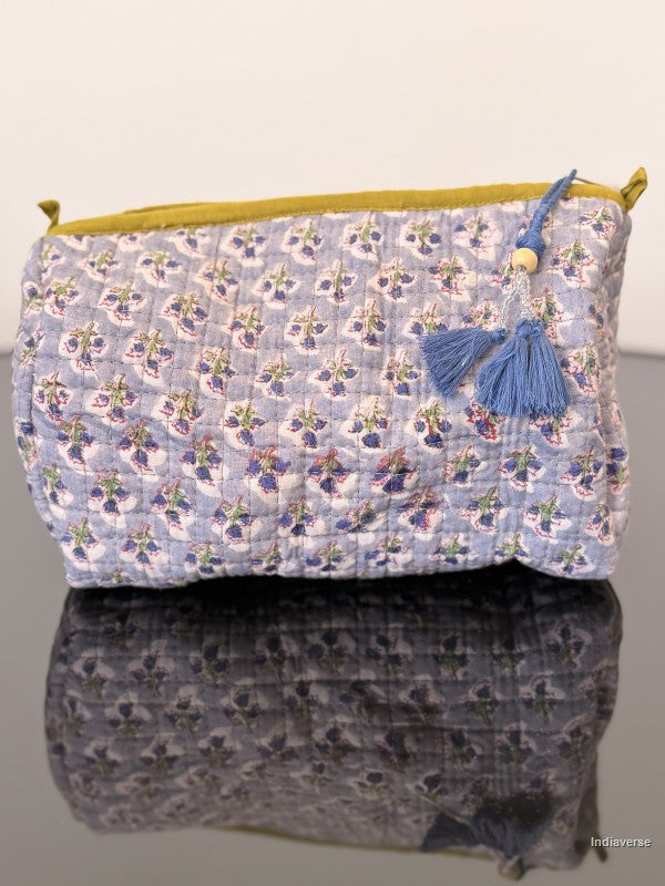 blue toiletry bag with small flowers sitting on a glass surface