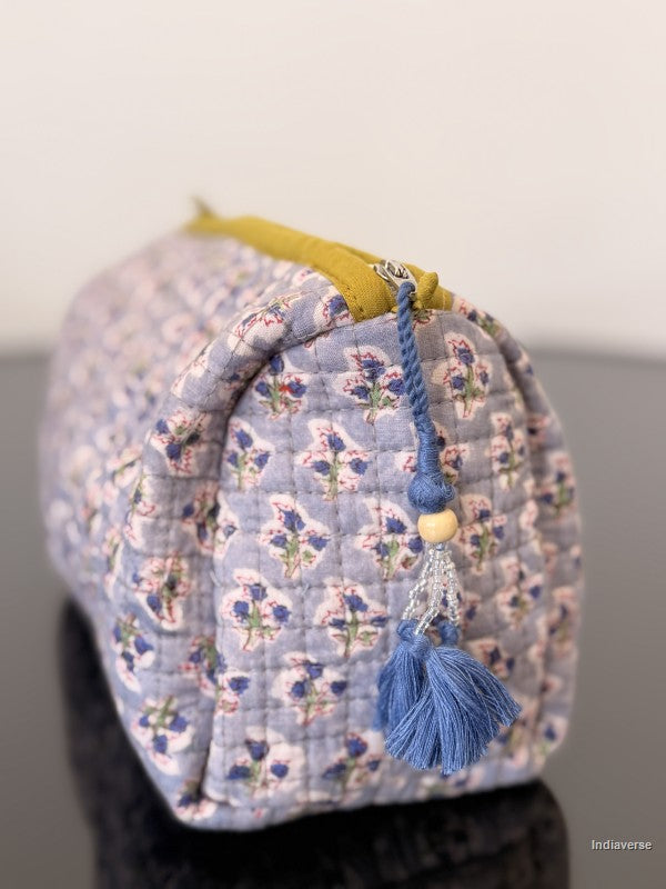 Floral-patterned fabric bag with a blue tassel on a plain background
