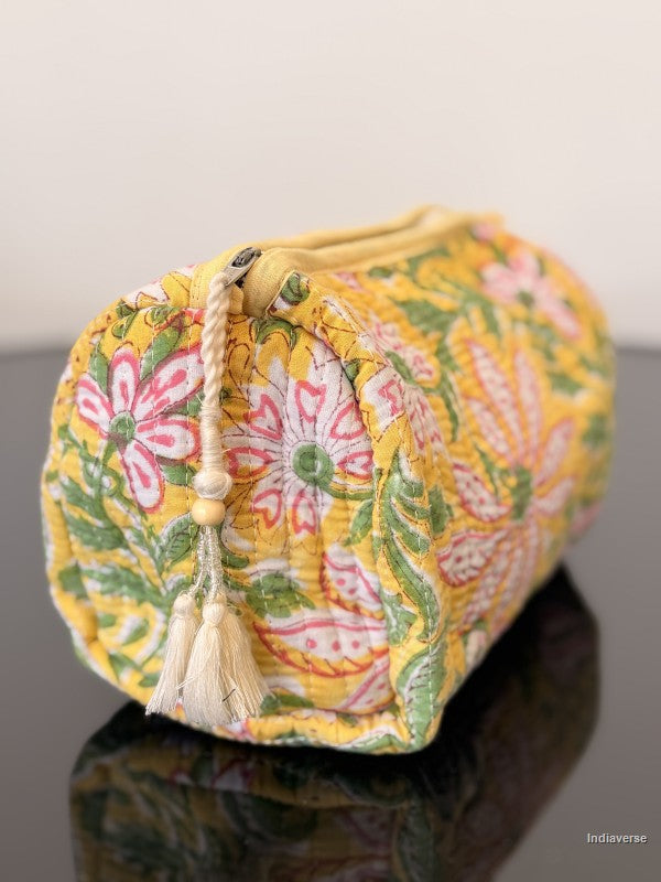yellow pouch with floral pattern and tassel sitting on a glass surface