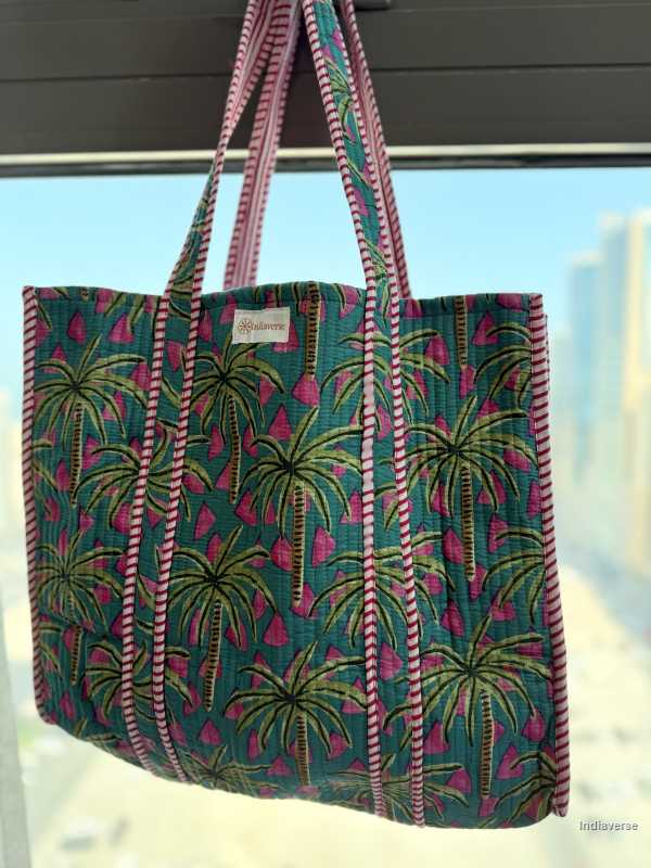 Tropical patterned tote bag with a visible brand label against a blurred outdoor background