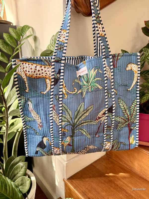 Tropical-themed tote bag with animal prints and stripes on a wooden surface.