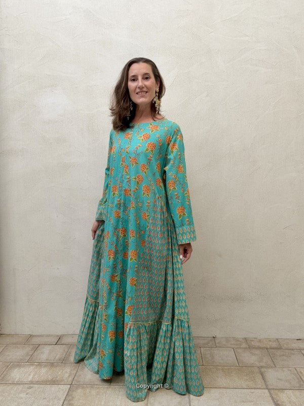 Woman wearing a teal floral dress against a plain background