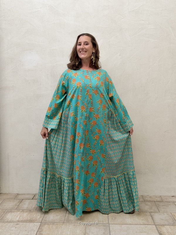 Woman wearing a teal floral dress against a plain background
