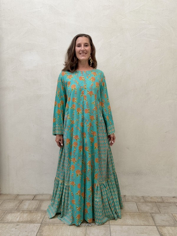 Woman wearing a teal dress with orange floral pattern against a plain background