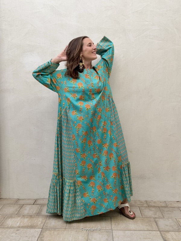 Woman wearing a teal floral dress against a plain background