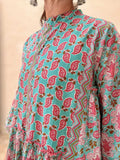Woman wearing a midi size cotton dress with floral print standing in front of a beige wall