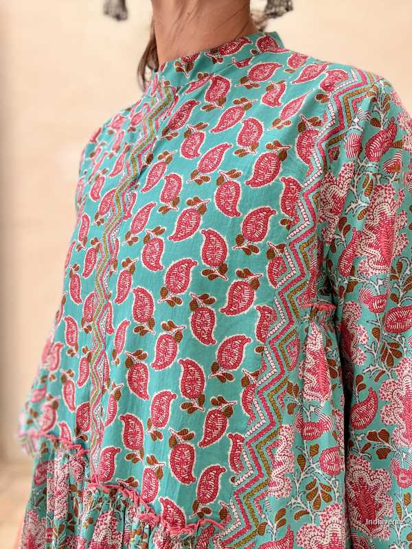 Woman wearing a midi size cotton dress with floral print standing in front of a beige wall