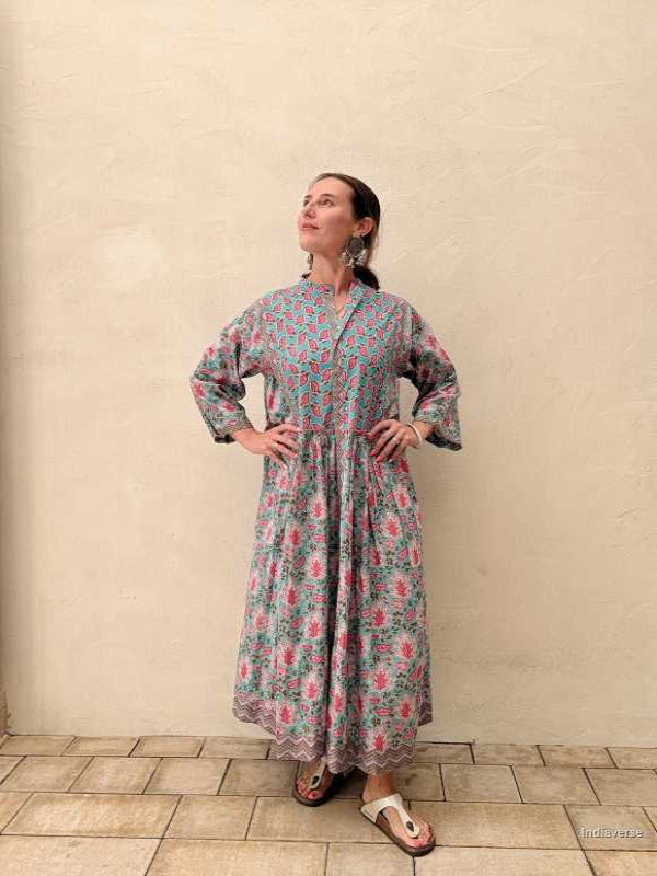 Woman wearing a midi size cotton dress with floral print standing in front of a beige wall