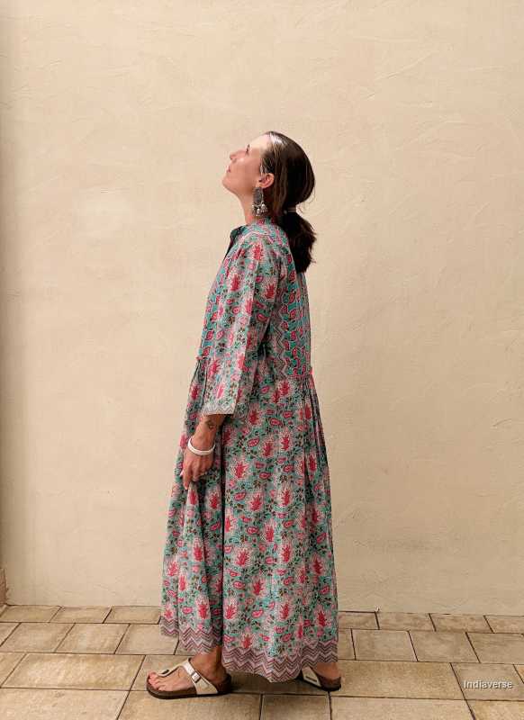 Woman wearing a floral dress against a beige wall.