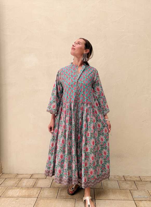 Woman wearing a midi size cotton dress with floral print standing in front of a beige wall