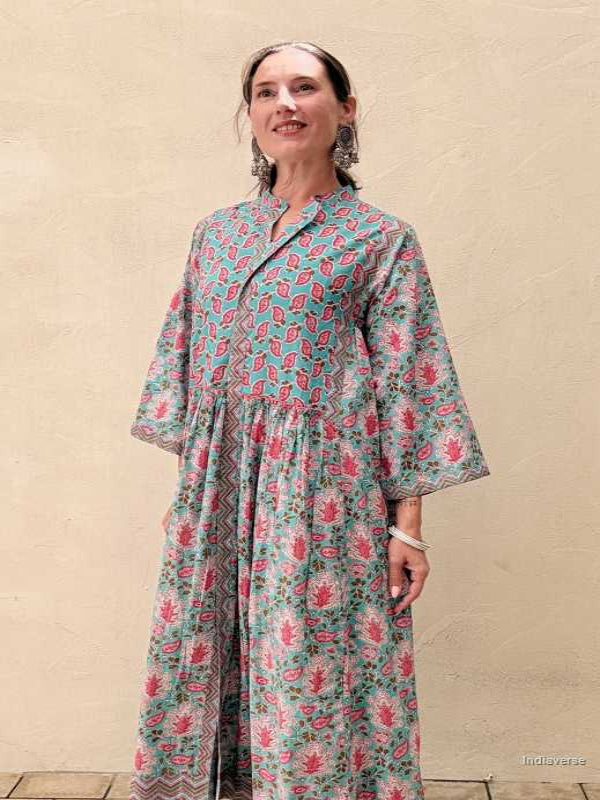 Woman wearing a midi size cotton dress with floral print standing in front of a beige wall