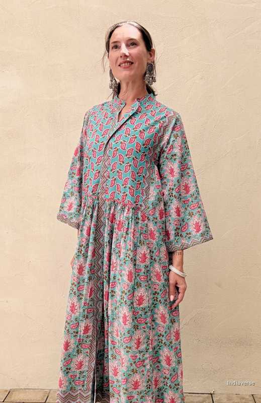 Woman wearing a midi size cotton dress with floral print standing in front of a beige wall