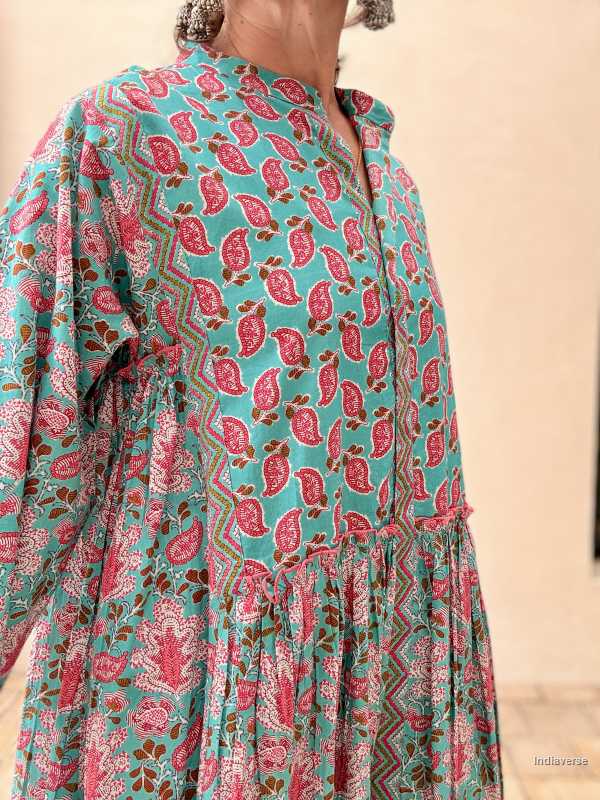 Woman wearing a midi size cotton dress with floral print standing in front of a beige wall