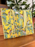 Yellow fabric tote bag with jungle animal pattern on a wooden surface