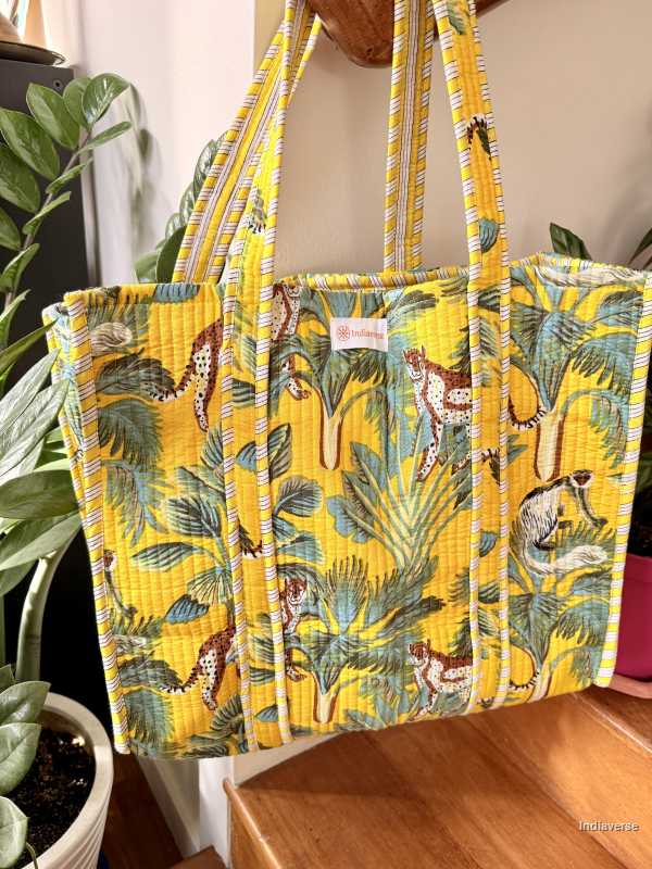 Yellow tote bag with animal and leaf pattern on a wooden surface