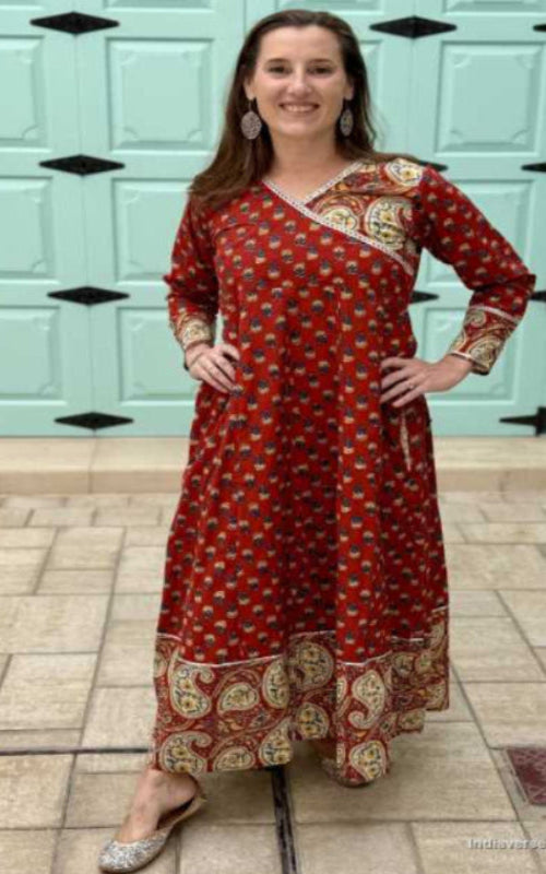 Woman wearing a full length and full sleeve maroon red wrap dress and silver detailing and paisley design trim