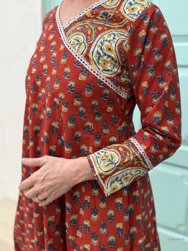 Woman wearing a full length and full sleeve maroon red wrap dress and silver detailing and paisley design trim